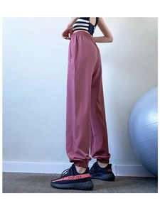 Detail view of pink loose-fit joggers featuring elastic high waist and side hidden zipper pockets