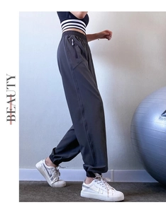 Detail view of dark grey athletic joggers featuring elastic waist and zip pockets for women