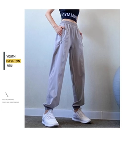 Close-up detail of high waist elastic band and metal zipper pocket on light grey jogger pants