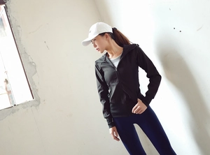 Détail d'une veste de sport noire ajustée à capuche et d'un legging bleu pour femme