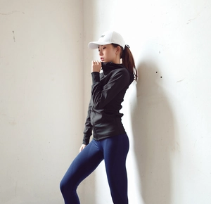 Détail d'une veste de sport noire cintrée et d'un legging de yoga bleu marine femme