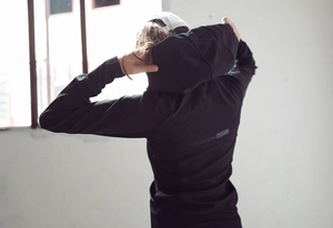 Détail du sweat à capuche de sport noir avec l'imprimé RISEANDSHINE dans le dos