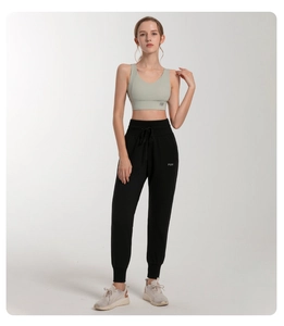 Detail of high-waisted black joggers and light green sports vest with PUH logo