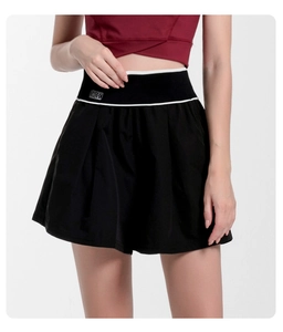 Detail of high-waisted black tennis skirt with pleated hem and contrast BK logo waistband