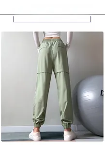 Detail of mint green jogger pants featuring layered splicing and side zipper accents