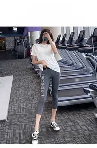 Detail of high waist grey yoga leggings with white logo print in a gym setting