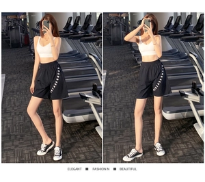 Dettaglio dei pantaloncini fitness neri larghi con stampa di lettere laterali e tessuto