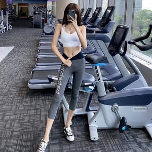 Women's white sports bra and high-waisted gray yoga leggings with text print detail