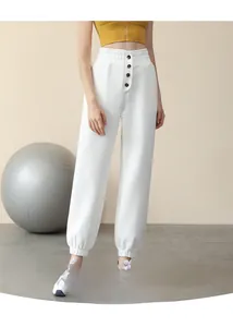 Detail of white high-waisted loose joggers featuring a multi-button waist and elastic cuffs
