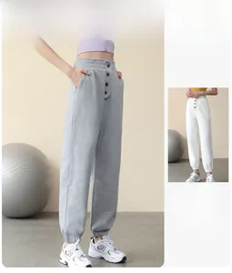 Detail of high waist joggers with elastic cuffs and decorative buttons for fitness
