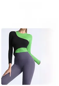Détail du haut court asymétrique noir et vert avec un legging de yoga violet taille haute