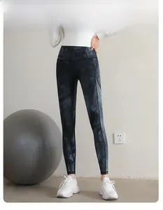 Detail of high-waisted tie-dye yoga leggings worn by a model with a grey yoga ball accessory