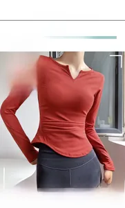 Close-up of V-neckline and ruched waist detail on women's rust red yoga long sleeve top