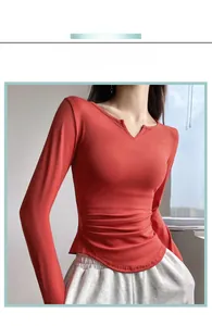 Detail of V-neck stitching and side ruched drawstring on rust red long sleeve sports top