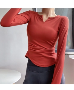 Detail view of V-neck long sleeve sports top with side ruching and curved hemline