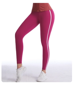 Gros plan d'un legging de yoga taille haute rose rouge avec bandes blanches sur le côté