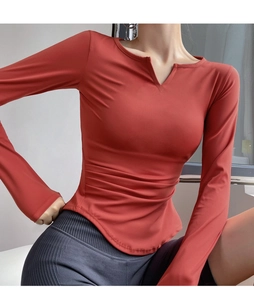 Detail view of brick red slim fit yoga top with V-neckline and side waist pleats