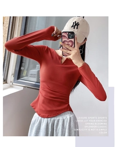 Detail of dark red V-neck long sleeve gym top with side ruching and stretch fabric texture