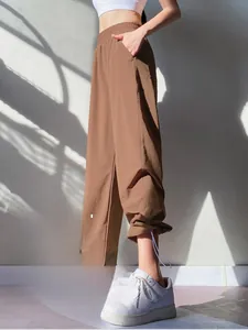 Detail view of high waist loose brown joggers with side white stitching and pocket