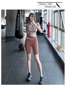 Close-up of high-waisted fitness shorts with contrast panels in brick red and grey