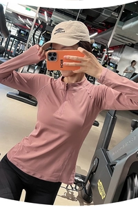 Détail du haut de fitness rose sec avec demi-zip et trous pour les pouces fonctionnels