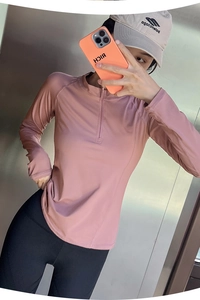 Selfie miroir détaillé d'un haut de sport rose ajusté à manches longues et demi-zip
