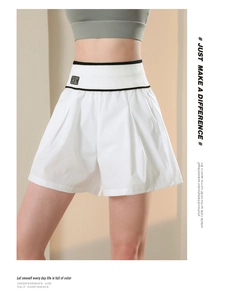 Dettaglio di pantaloncini sportivi bianchi a vita alta con vita nera a contrasto e patch BK