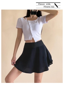 Dettaglio di gonna sportiva a pieghe nera a vita alta con crop top bianco a costine