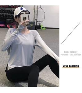 Détail de la fente latérale sur un haut de sport gris à manches longues et leggings noirs