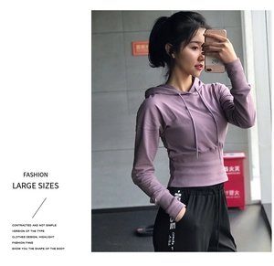 Détail d'un sweat à capuche court violet et d'un legging noir porté par un mannequin