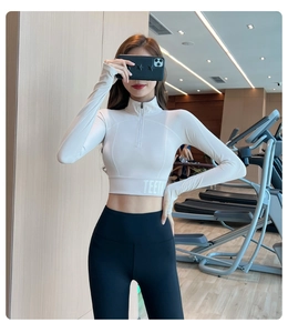 Détail des poignets passe-pouce et du logo TEETK sur un haut de yoga blanc cassé