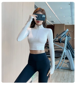 Détail du haut de yoga blanc à demi-zip avec passe-pouces et leggings de sport noirs