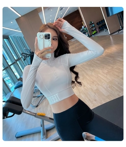 Détail d'un haut de yoga blanc avec demi-zip, col montant et ourlet ajusté élastique
