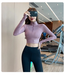 Détail du haut de sport rose à demi-zip montrant le tissu et le lettrage TEETK en bas