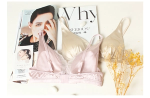 Flat lay of silk lace bras in pink and champagne colors with decorative props