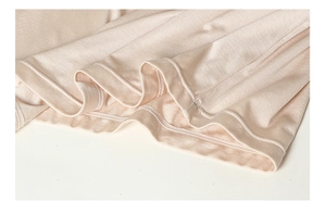Close-up of silk camisole hem showing smooth champagne fabric and fine double-needle stitching