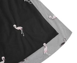 Detailed macro view of pink flamingo embroidery on multi-layered black mesh skirt