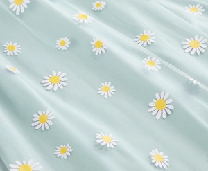 Detailed macro view of mint green mesh fabric with white and yellow daisy floral patterns