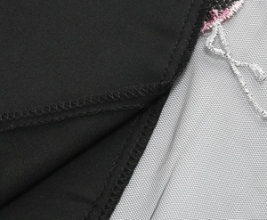 Macro view of high-waist skirt featuring floral embroidery on white mesh fabric