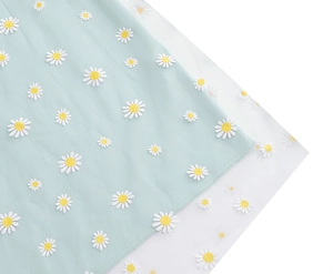 Detailed close-up of white daisy embroidery on light blue mesh fabric with neat stitching