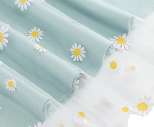 Close-up of mint green skirt featuring white daisy prints on a delicate mesh overlay