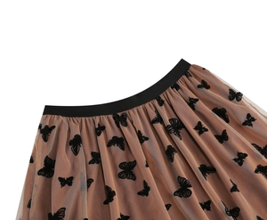 Dettaglio del motivo a farfalle nere sulla gonna a pieghe in mesh beige chiaro