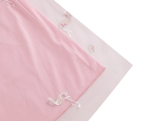 Detailed close-up of flamingo embroidery on light pink mesh and plain fabric textures