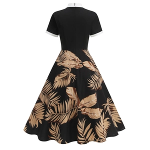 Detail of a vintage 50s style dress featuring a black bodice and palm leaf print skirt