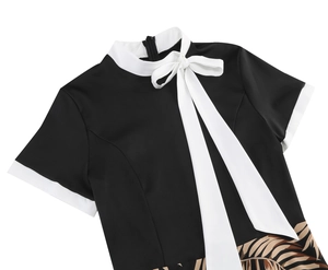 Detailed view of black vintage dress with white bow neck and palm leaf prints