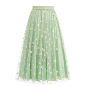 Detailed close-up of delicate white daisy embroidery on light green mesh tulle fabric