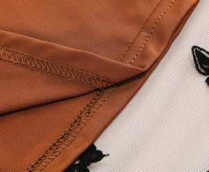 Dettaglio del tessuto in maglia caramello con ricamo a farfalla nera su rete bianca