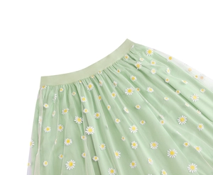Macro view of light green mesh skirt showing white daisy floral prints and texture
