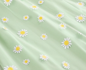 Detailed macro view of embroidered white daisies on light green breathable mesh fabric