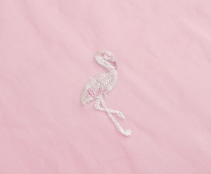 Close-up of intricate flamingo embroidery on premium light pink cotton blend fabric